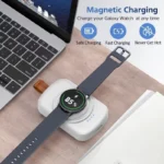 Magnetic wireless smartwatch charger power bank with keychain clip and smartwatch resting on charging surface.