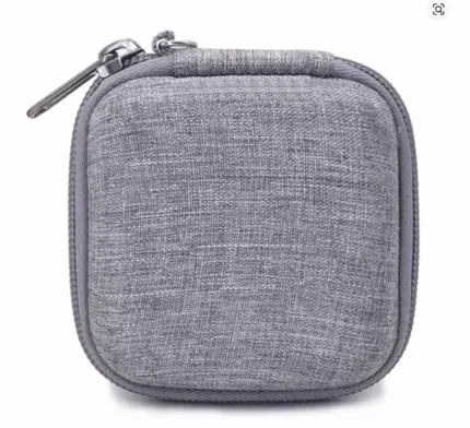 Grey portable cable organizer bag open on a white surface next to a laptop showing stored charger and cables.